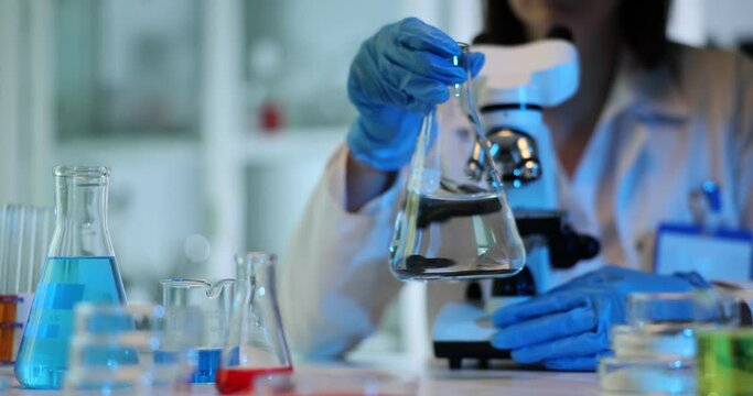 Scientist studying clear liquid in flask in laboratory
