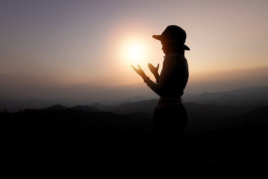 Person hands open palm up worship. Silhouette of prayer woman worship God in the morning with sunrise sky background.  God helping repent catholic.