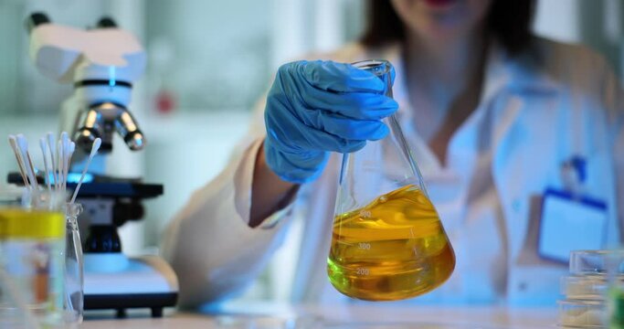 Scientist mixing chemicals or oil in a flask in laboratory