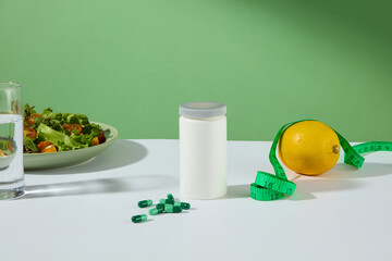 Creative designing template of front view on green background, white table with a bottle of weight losing medicine displayed above, next to measuring tape, drugs of green color and fresh ingredients