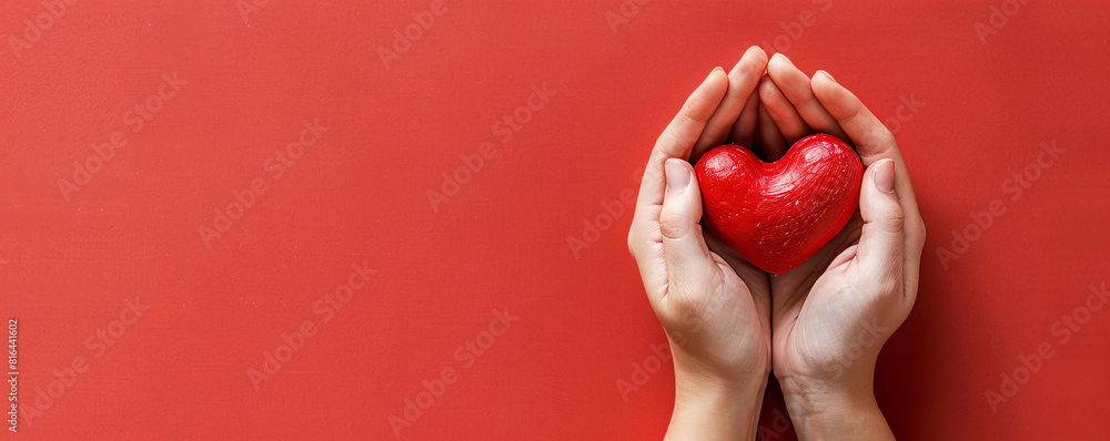 Poster against a minimalist, solid-colored background, two hands present a bright red heart, creating a str