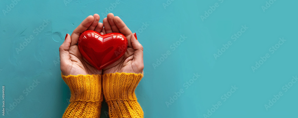 Poster against a minimalist, solid-colored background, two hands present a bright red heart, creating a str