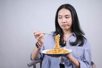 Young Asian Woman Bored To Eat Noodle While Looking To Side Isolated On White Background
