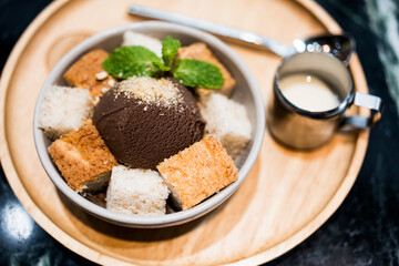 A delectable chocolate ice-cream served with sliced bread and a shot of sweetened condensed milk on...