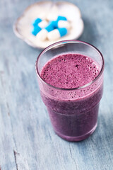 Glass of Protein Shake with milk and blueberries and Creatine capsules. Concept for Sport nutrition. Rustic wooden background. Close up.
