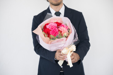 花束を持つ男性　母の日や誕生日、記念日の贈り物に　いつもありがとう