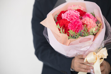 花束を持つ男性　母の日や誕生日、記念日の贈り物に　いつもありがとう