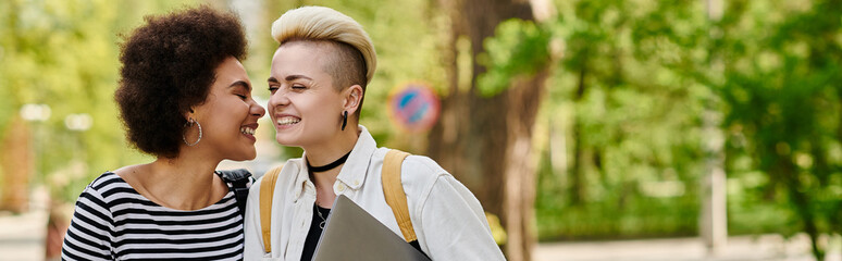 Naklejka premium Multicultural lesbian couple in casual attire walking near university campus.