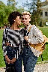 A pair of young women, stylish in casual attire, striking a pose together in a picturesque park