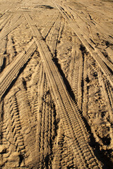 Sandy surface with tyre tracks crisscrossing in various directions