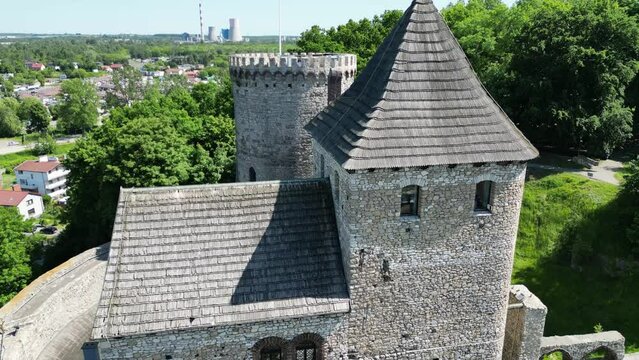 Medieval Bedzin castle with a tower, walls, and courtyard during a beautiful summer day surrounded by lush greenery under a clear blue sky