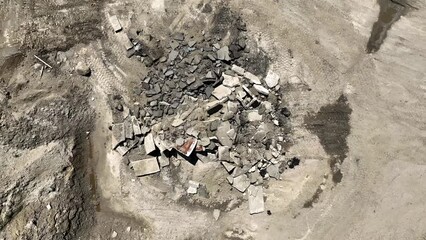 Pile of broken concrete slabs built up in dirt stockpile yard, aerial
