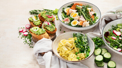 Spring fresh food with green leaf. Salads with strawberries, bacon and ravioli on light wooden...