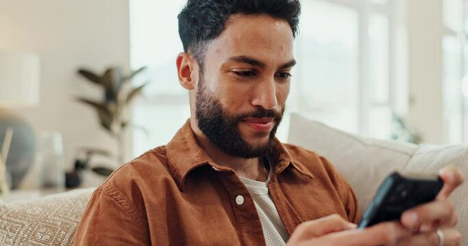 Phone, text and man in a home with social media, internet and website scroll on a lounge sofa. Video, meme and smile relax at a home with news app, streaming and typing online for web post comment