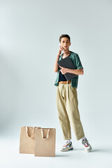 A stylish young man effortlessly balancing shopping bags and a cell phone, exuding confidence and...