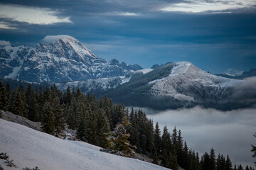 beautiful spring morning on the mountains with view of the alps with clouds, sun, spruce trees and snow