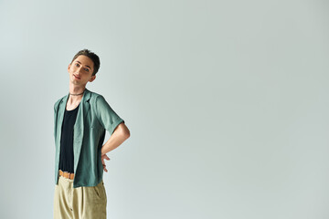 A young queer person confidently posing against a neutral background.