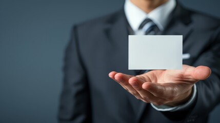 A man in a business suit holds a business card