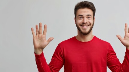 Fototapeta premium A man smiles in a red shirt, hands raised in front of him