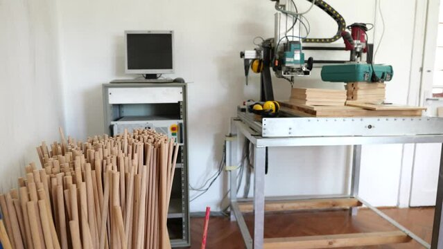 Container of dowels, computer connected to wood cutting machine in game factory.
