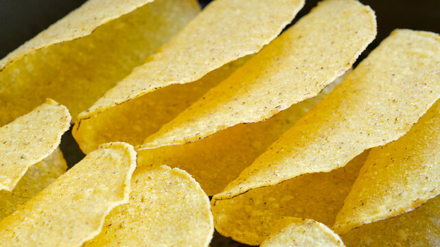Closeup of a group of empty taco shells on a black background.
