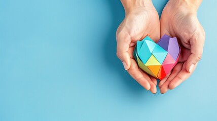A person is holding a colorful paper heart