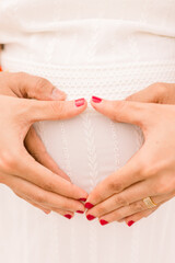 A pregnant Indian woman and her husband make a heart shape with their hands. 