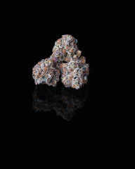 Grouped cannabis nug on black reflective surface