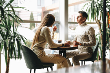 Two Friends Enjoying Casual Conversation Over Coffee at a Modern Cafe During Daytime