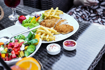 Delicious Plate of Fried Chicken, French Fries, Salad and a Glass of Wine