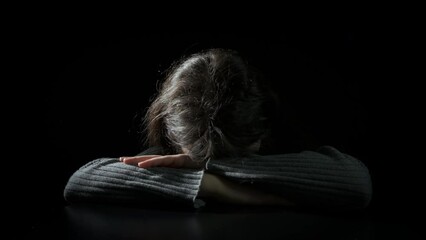 Sad teen face sit on black background. A view of sad teen girl face sitting in loneliness against black background. - Powered by Adobe