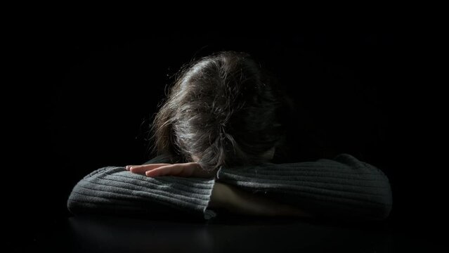 Sad teen face sit on black background. A view of sad teen girl face sitting in loneliness against black background.