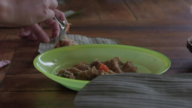 Hands craft the traditional Indonesian dish Sate lilit with a spoon, delicately wrapping minced meat in fragrant leaves. Footage showcases the artistry and cultural richness of Indonesian cuisine.