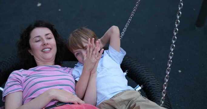 Family day or spending time together concept. Cute caucasian brunette mother having fun with her kid son oa a playground. Outdoor activities