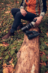 Man using binoculars and camera for bird and animal watching in nature.