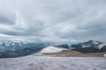 Dramatic panoramic view from big glacier on rocky hill to wide large snow-capped mountain range in...