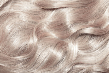 Blond hair close-up as a background. Women's long light brown hair. Beautifully styled wavy shiny...