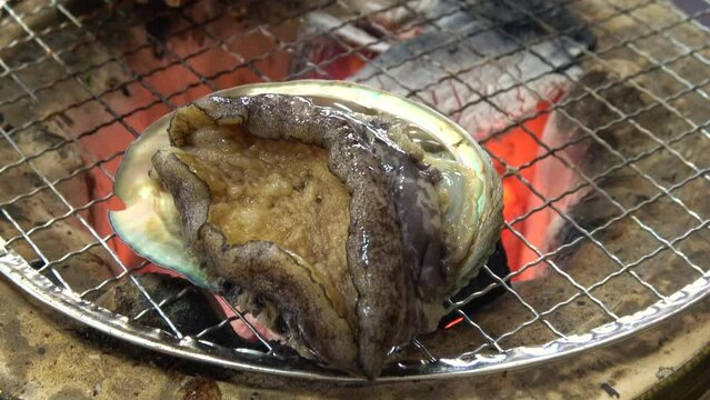 三重県産の殻付きアワビを炭火で踊り焼き クローズアップ  4K