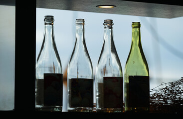 Many glass wine bottles displayed on the window shelf in the room