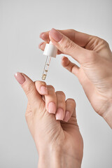 Women's hands apply cuticle oil with a pipette