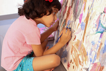 Indian Girl child doing painting on canvas. Artist home school education learning Concept.
