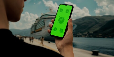 Hand holding a phone with a green screen, ideal for mockups and travel-related design showcases