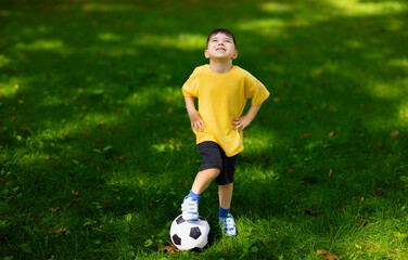 boy kid playing football in park on grass.child with ball in hands lying on ground.siblings,...