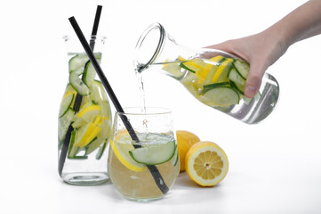 Nalewać wodę do szklanki, orzeźwiający napój z cytryną i ogórkiem nalewany z karafki do szklanki 
