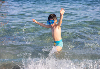 cute kid with hat on beach against sea or is having fun in summer vacation.boy with snorkel, diving...