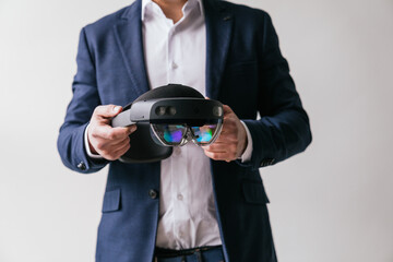 A close-up of a businessman in a suit holding a virtual reality headset, focusing on the advanced...