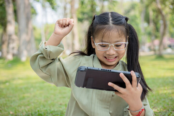 Girl playing video game with handheld game console at garden