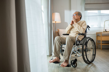 Lonely older thoughtful sad old man look outside windows in bedroom at retirement home, Asian senior man disabled feel depressed lonely sitting alone in wheelchair looking through window at hospital