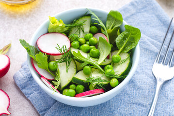 Spring, summer vegan salad with radishes, fresh cucumbers and green peas and herbs, seasoned with...