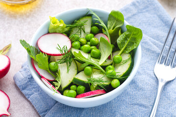 Spring, summer vegan salad with radishes, fresh cucumbers and green peas and herbs, seasoned with olive oil, balsamic and lemon. Spring plant based diet, clean healthy eating 